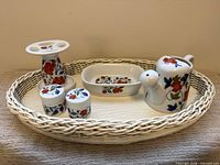 All five ceramic pieces arranged on wicker tray showing pattern and tray