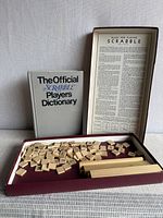 Maroon Scrabble set open with tiles, racks, rules sheet, grey dictionary