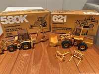 Both die-cast models with boxes and attachments on table