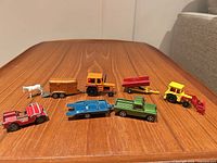 Group shot of all eight Corgi die-cast vehicles and accessories on wooden surface
