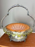 Bowl seated in ornate silverplate stand with arched handle
