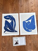 Both lithograph prints and information card laid on wood floor