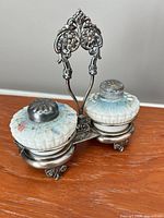 Front view of caddy with two shakers showing floral glass and silverplate handle