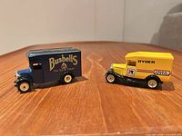 Blue Bushell’s and yellow Ryder die-cast vans side by side on table