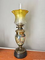 Full view of amber and clear oil lamp on wooden base