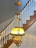 Full view of hanging lamp suspended on stairwell, showing shade, prisms, chains and canopy