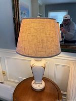 Full view of lamp lit showing distressed ceramic base and fabric shade