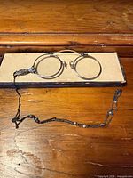Top view of spectacles resting on box lid with chain displayed