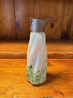 Front view of glass pitcher highlighting twisted form and green frit decoration