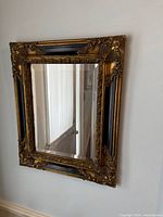 Front view of ornate black and gold framed mirror on wall