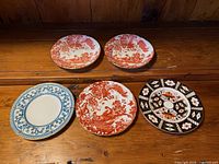 Five assorted Royal Crown Derby plates laid out, showing fronts and pattern variety