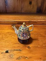 side view of cloisonné teapot on wood stand