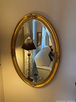 Front view of oval gold wood mirror hanging on wall