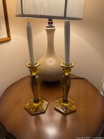 Pair of yellow glass candlesticks with candles displayed on table