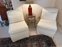 Front view of both cream slipper chairs next to side table