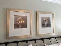 Both framed prints hanging side by side above bed