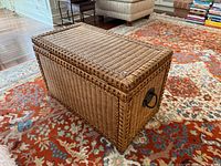 Three-quarter view of wicker storage chest showing front and side weave pattern