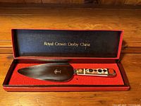 Cake slice in open box showing handle pattern and blade hallmark