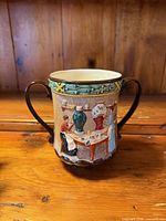 Front view of Royal Doulton loving cup showing relief scene and handles