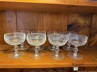 Eight Waterford Colleen coupe glasses on wooden shelf, full frontal view