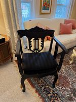 Front angled view of black armchair showing lyre back, arms, seat, legs