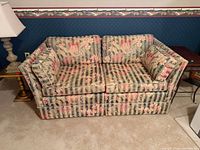 front view of floral two-seat sofa showing cushions and pillows