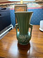 Front view of green McCoy double-handled vase on table