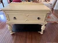 Front view of white sideboard showing drawer, legs, and black shelf