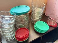 Group of glass bowls stacked with assorted colored lids showing quantity and style