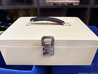 Closed beige cash box front view, chrome latch
