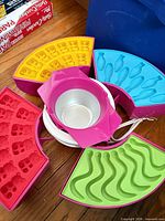 Full set showing heating base, metal pot, four quarter-circle silicone mold trays in different colours