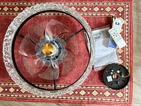 Ceiling fan assembly, clear blades, bezel, remote, mounting bracket, manual on rug