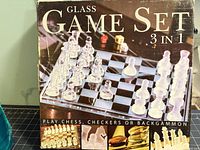 Front of retail box showing glass chess setup and 3-in-1 labeling