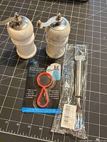 Two marble grinders, packaged silicone bottle holder, packaged stainless steel watermelon cutter on cutting mat