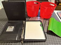 Organizer open showing calculator, card slots, 3-ring, notepad, pen; two red bins behind