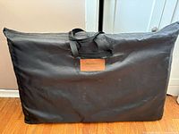 Folded hammock in black handled carry case showing Nanificent logo patch