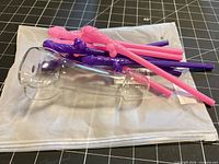 Glass phallic cup/pipe, multiple pink and purple penis straws on shipping bag