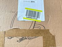 Sealed cardboard box showing shipping label, barcode and outline drawing of toilet seat hardware
