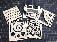 Five small square plywood knitting/crochet gauge organizers arranged on cutting mat