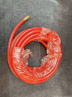 Coiled red air hose wrapped in plastic