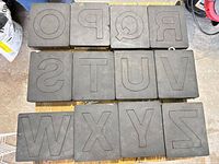 Twelve letter dies laid out in rows showing foam cutting faces