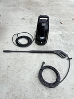 Full view of pressure washer, spray wand, hose and power cord on floor
