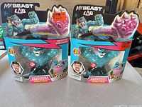 Front view of two sealed MrBeast Lab Iconic Tiger figures showing characters, price stickers, and intact blister packaging