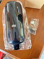 Front view of Tork black soap dispenser with keys and mounting screws in plastic bag