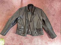 Front view of black leather biker jacket laid flat
