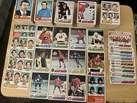 Stacks and spread of 1977 O-Pee-Chee hockey cards showing fronts of assorted player and team leader cards