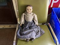 Full view of doll seated on chair showing clothing and overall size