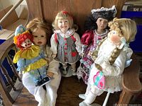 All five dolls seated and standing on wooden bench