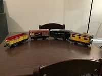Group shot of four Marx tinplate train cars: stock car, box car, tender, caboose