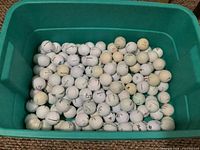 Top view of bin containing assorted used white golf balls